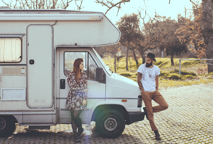 man and woman standing next to a camper